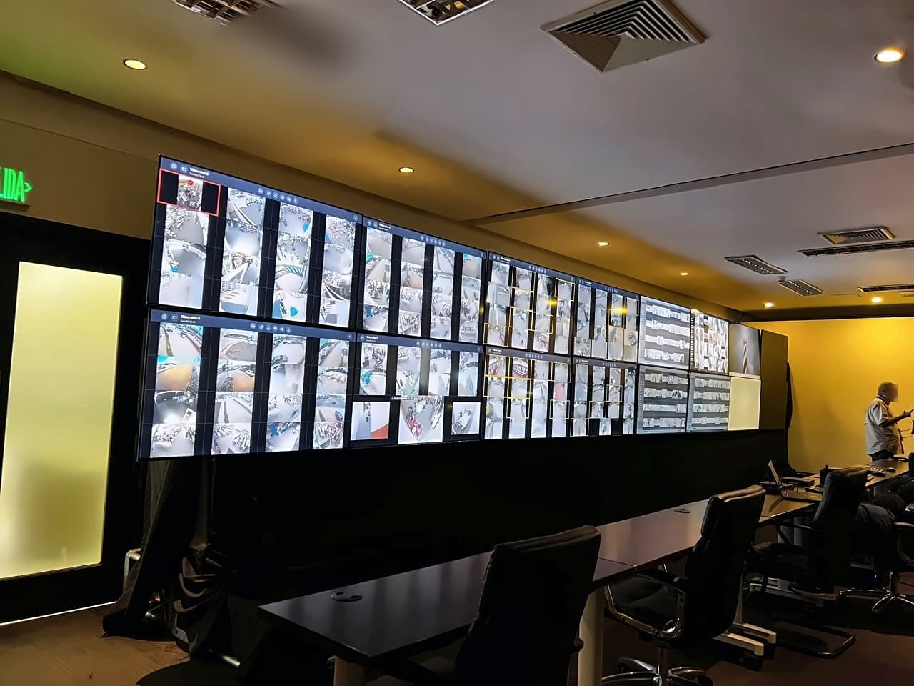 Muro de video del centro de control de los Juegos Centroamericanos y del Caribe Santo Domingo 2026: mosaicos de cámaras de las sedes sobre la sala de operadores