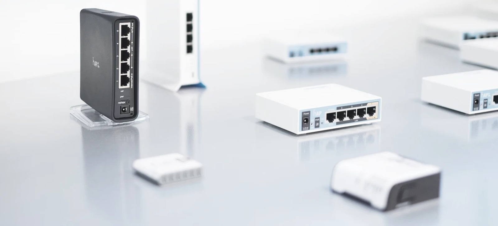 Familia de routers MikroTik fotografiada en estudio sobre una mesa blanca