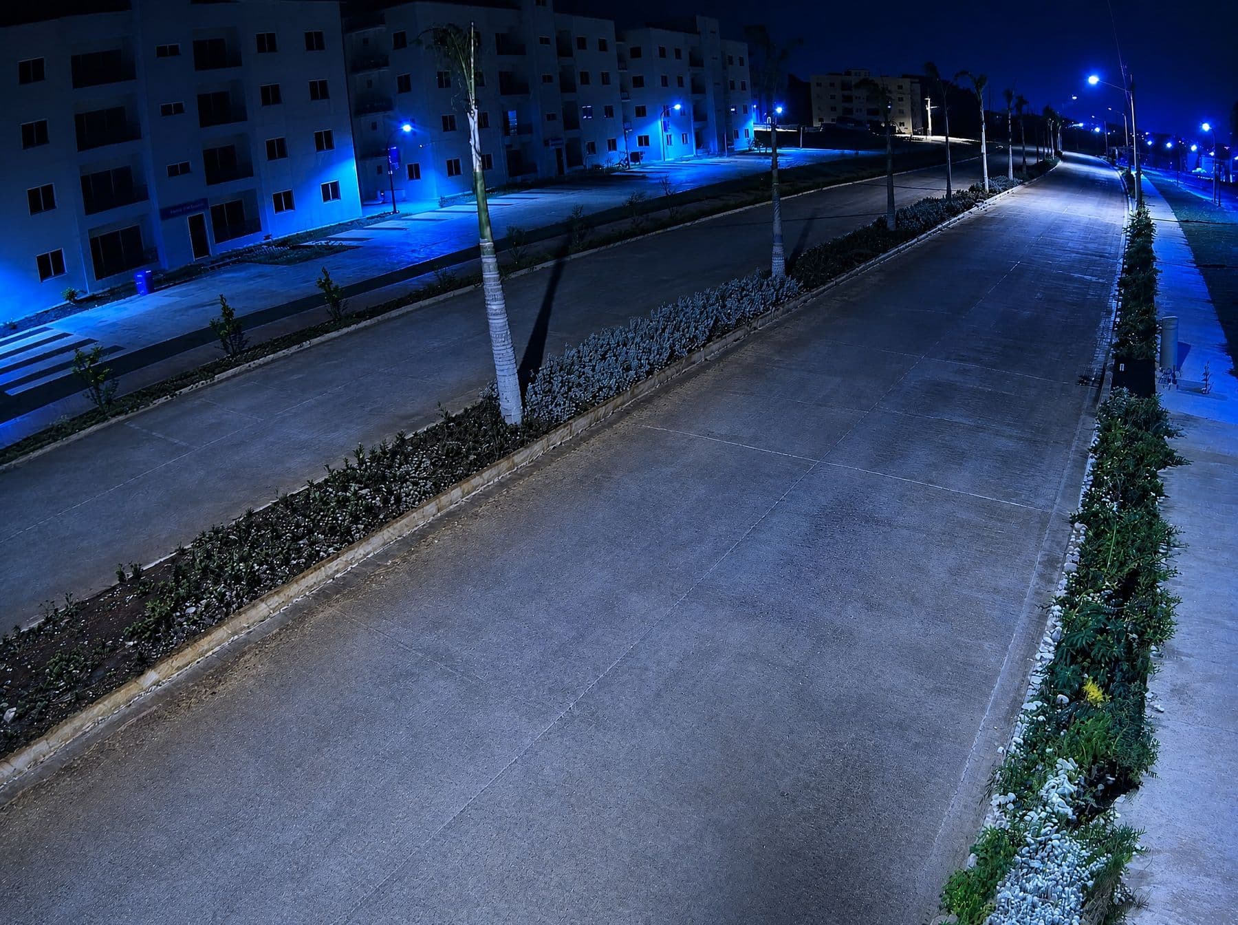 Vista nocturna de una cámara de videovigilancia sobre una avenida residencial iluminada, sin personas