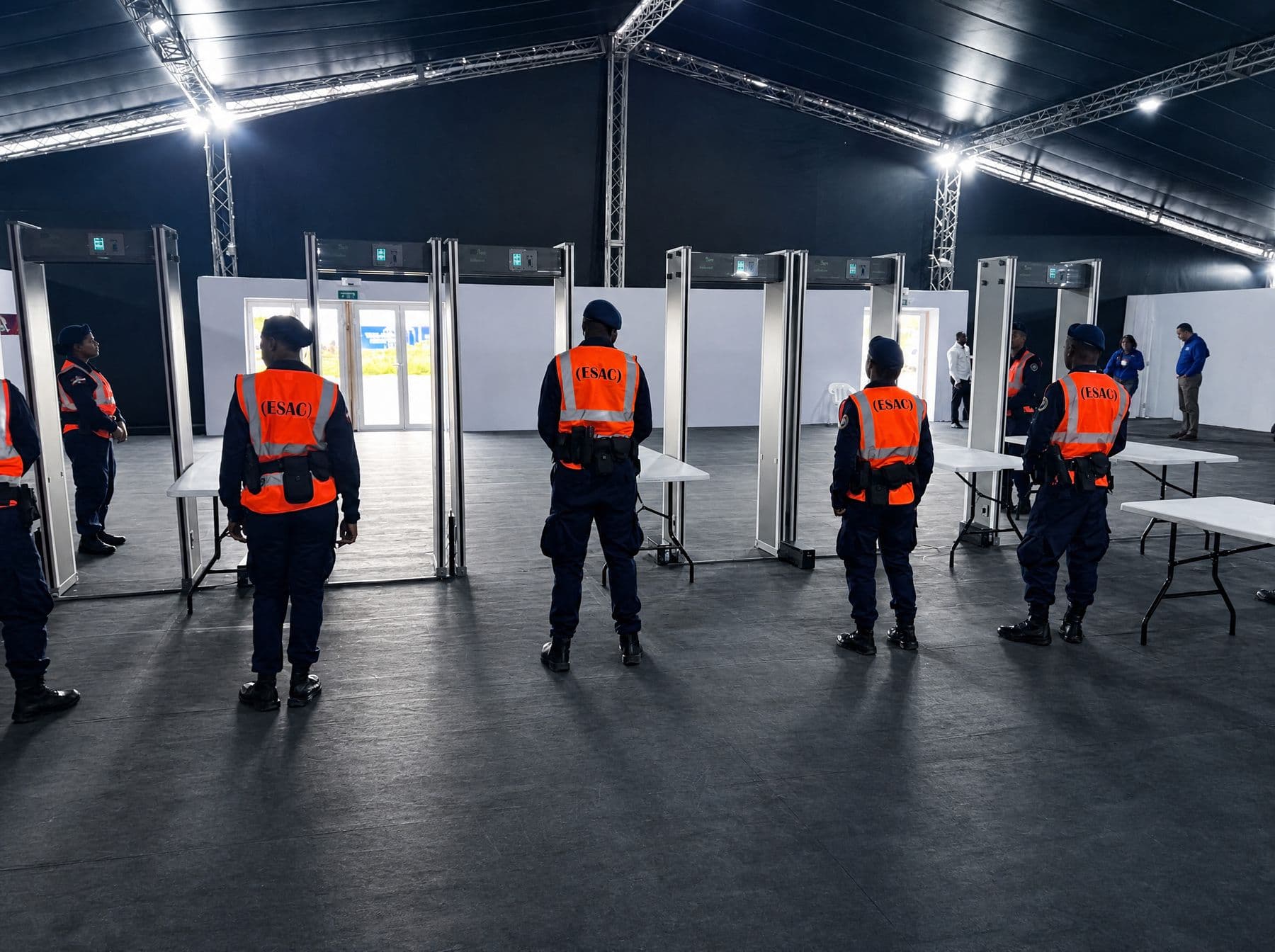 Interior de la carpa de control de acceso con arcos detectores y personal de seguridad