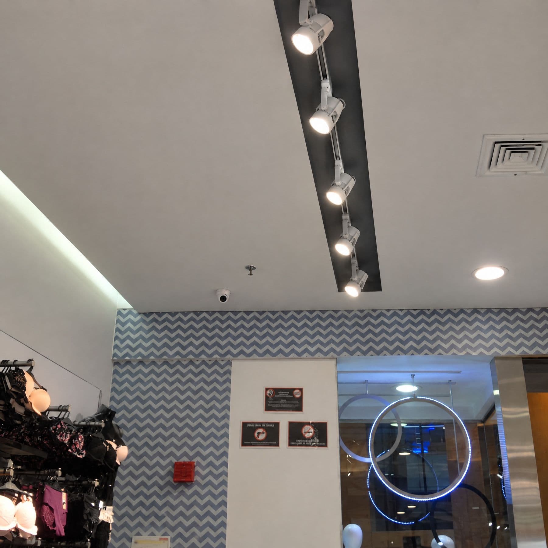 Cámara domo compacta en el techo de la sala de ventas del proyecto Balú, sobre la pared de papel tapiz en zigzag