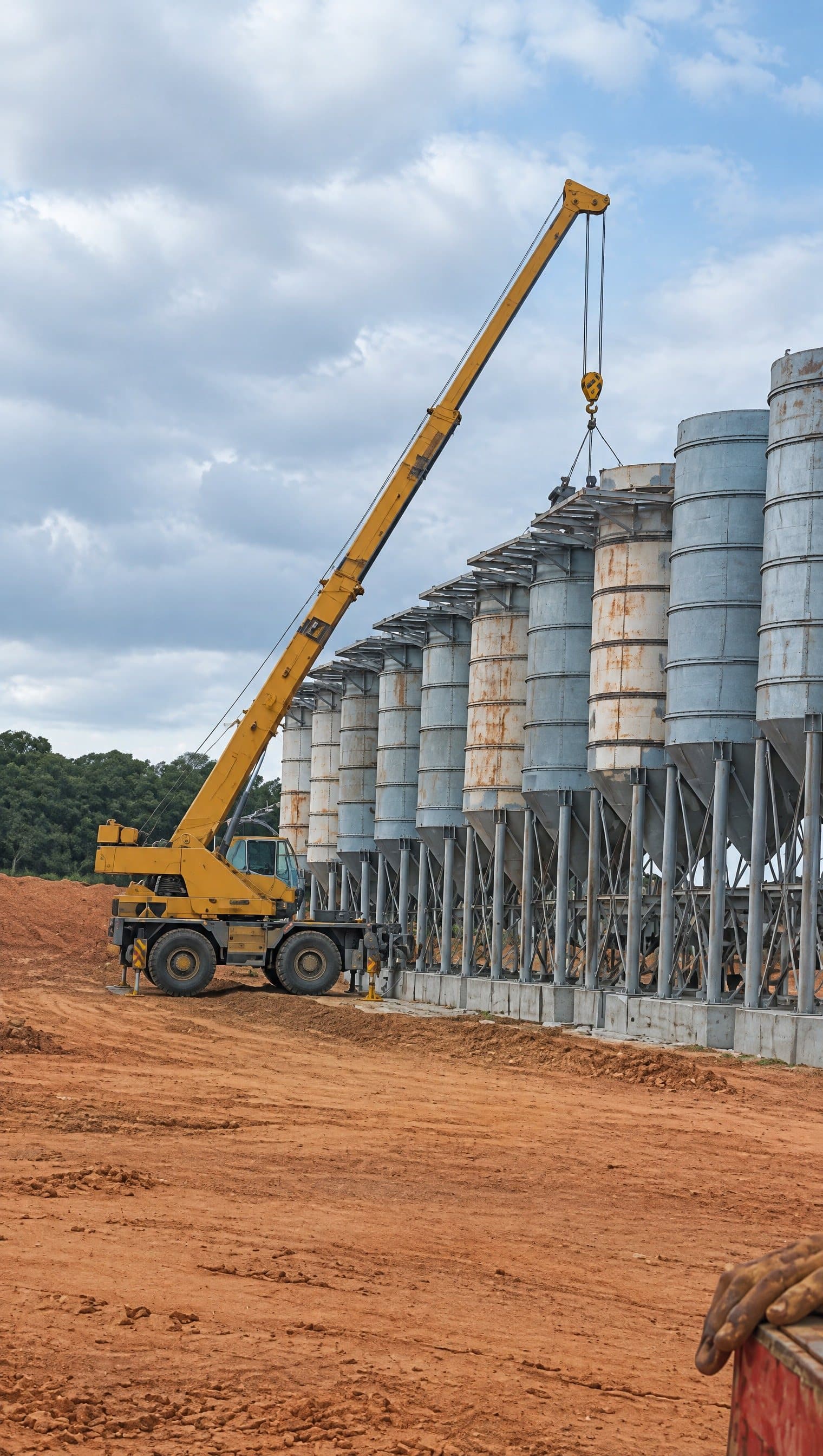 Grúa móvil montando una hilera de silos metálicos en una planta minera en construcción