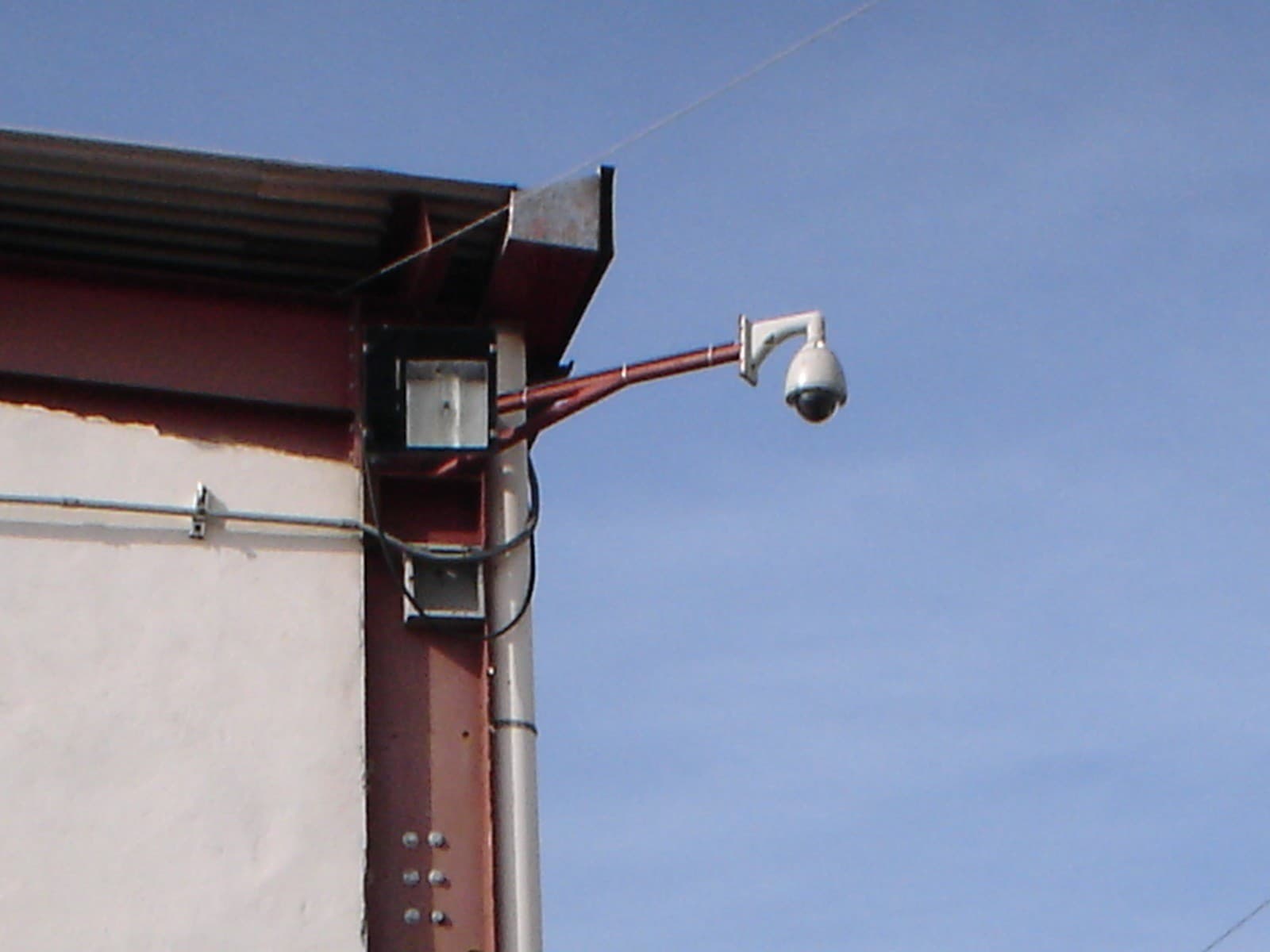 Cámara domo PTZ instalada en brazo metálico en la esquina exterior de una nave industrial en Puerto Ordaz